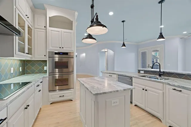 a kitchen with granite countertop a sink cabinets and stainless steel appliances