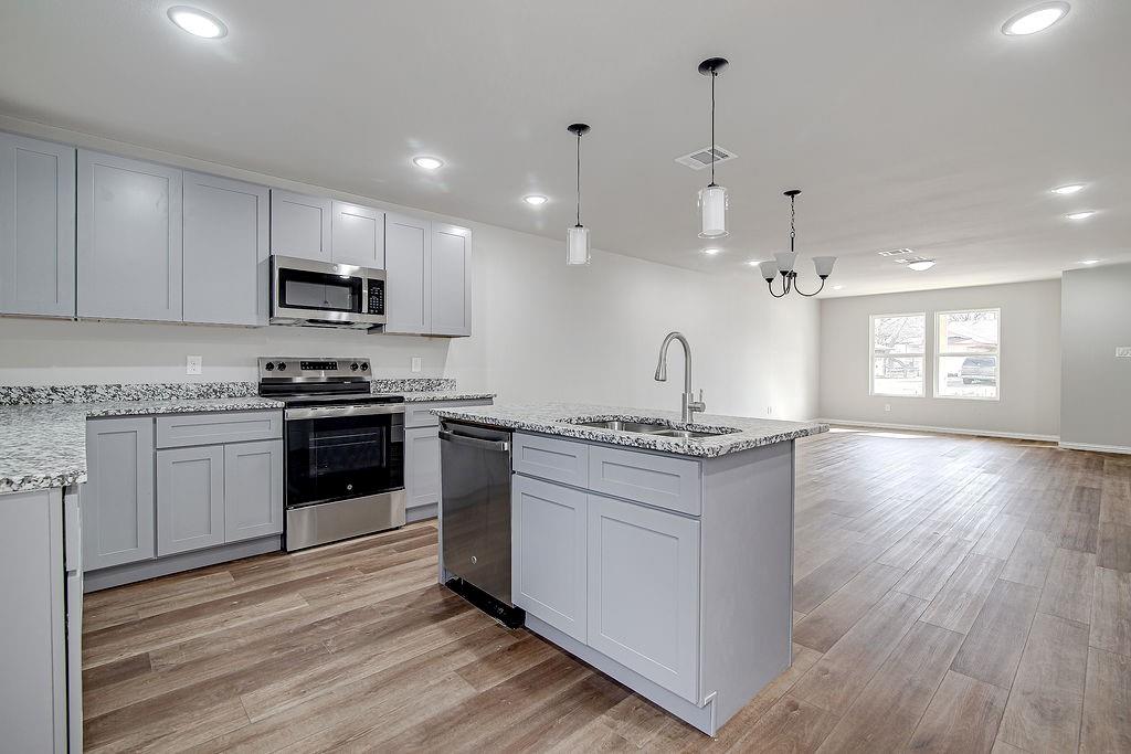 333 North Field Street Burleson, TX 76028 - Photo 30 of 35 a kitchen with stainless steel appliances granite countertop a stove a sink and a microwave