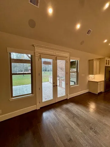 a view of an empty room with a window and wooden floor