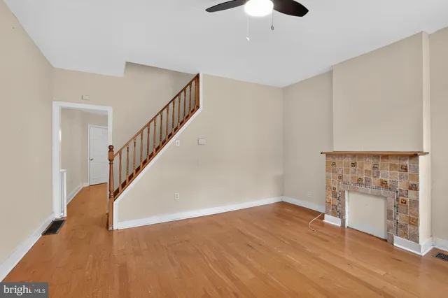 a view of an empty room with wooden floor and a fireplace