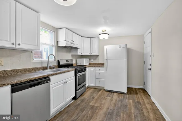 a kitchen with a white cabinets and wooden floor