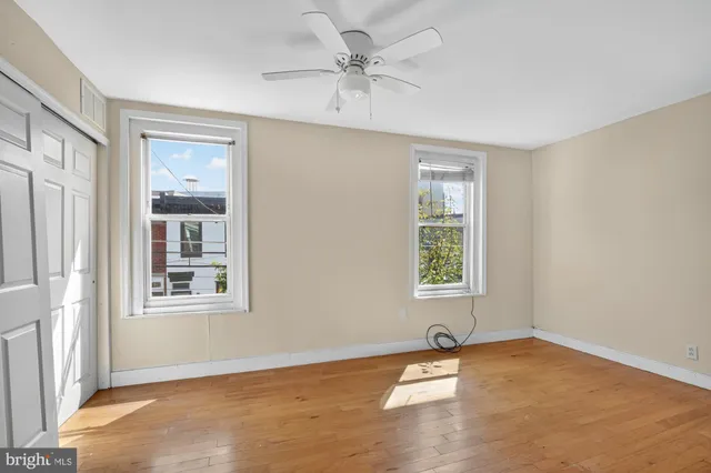 an empty room with a window and a ceiling fan