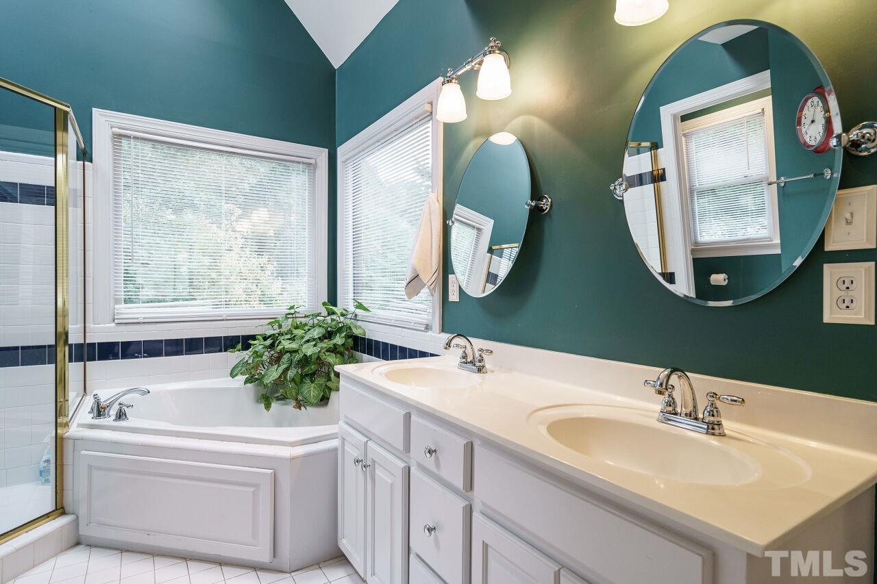 7800 Laurel Mountain Road Raleigh, NC 27613 - Photo 16 of 31 a bathroom with a two sinks a large mirror and a bathtub next to a window