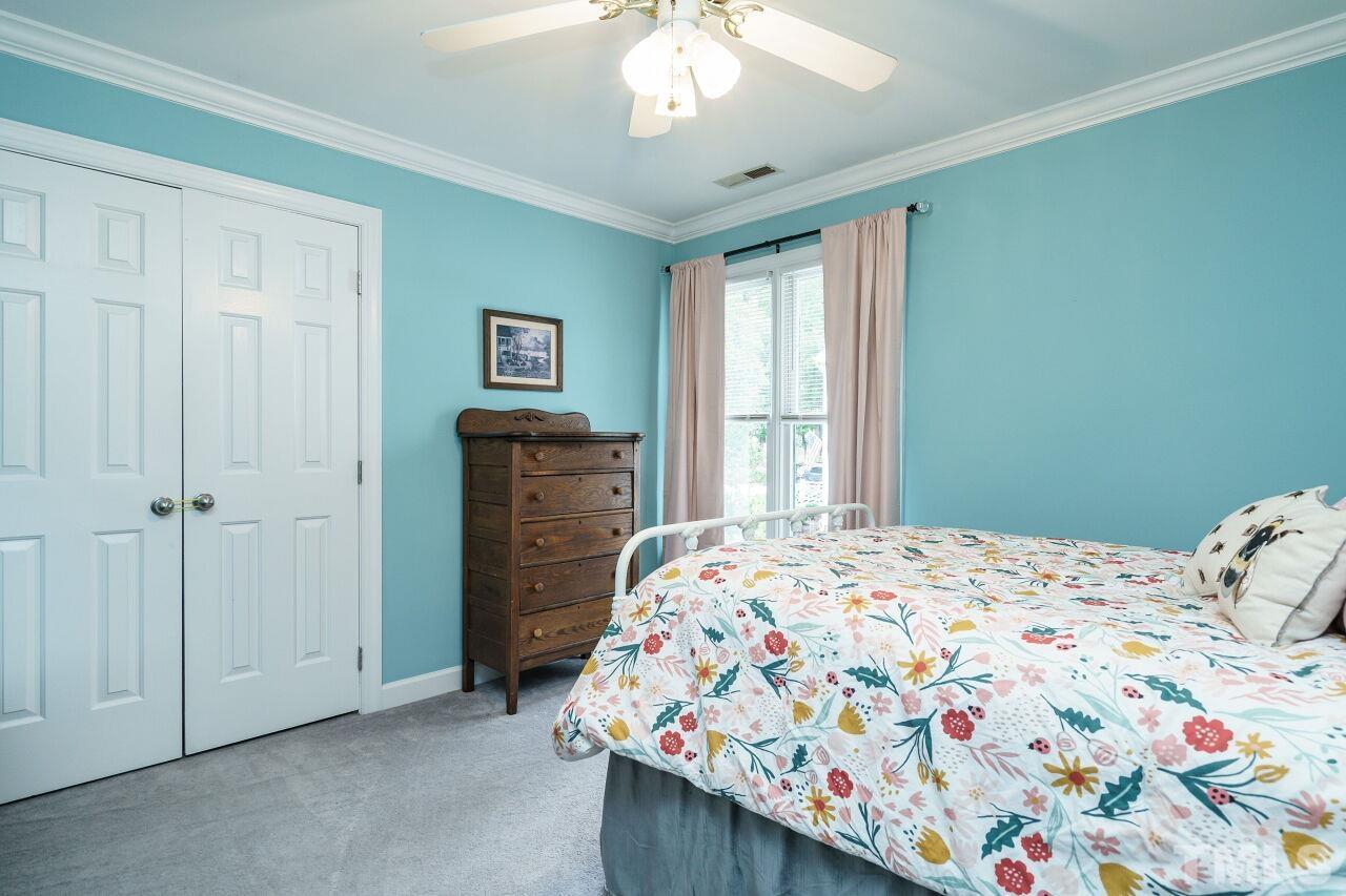 7800 Laurel Mountain Road Raleigh, NC 27613 - Photo 20 of 31 a bedroom with a bed and a chandelier