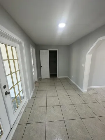 an empty room with windows and chandelier fan