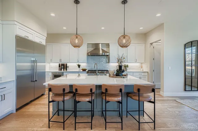 a kitchen with stainless steel appliances kitchen island granite countertop a dining table chairs and white cabinets