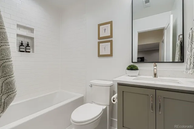 a bathroom with a toilet a sink a mirror a bathtub and vanity