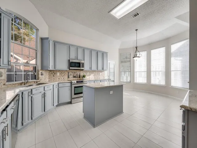 a large kitchen with stainless steel appliances granite countertop a stove a sink and a granite counter tops