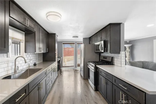 a kitchen with granite countertop a sink wooden cabinets and stainless steel appliances