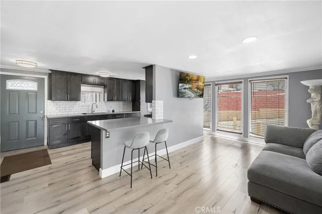 a living room with stainless steel appliances kitchen island granite countertop a couch a dining table and chairs