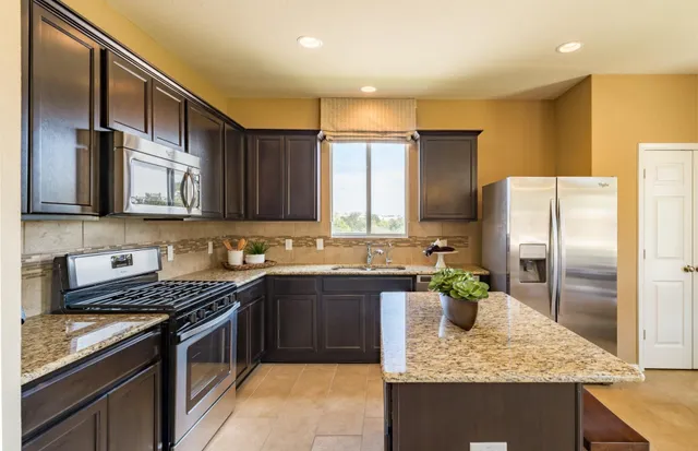 a kitchen with stainless steel appliances granite countertop a sink stove and refrigerator
