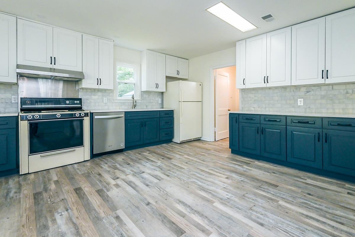 4934 Byron Road Memphis, TN 38122 - Photo 9 of 25 Kitchen with white cabinetry, light hardwood / wood-style flooring, white appliances, blue cabinetry, and decorative backsplash