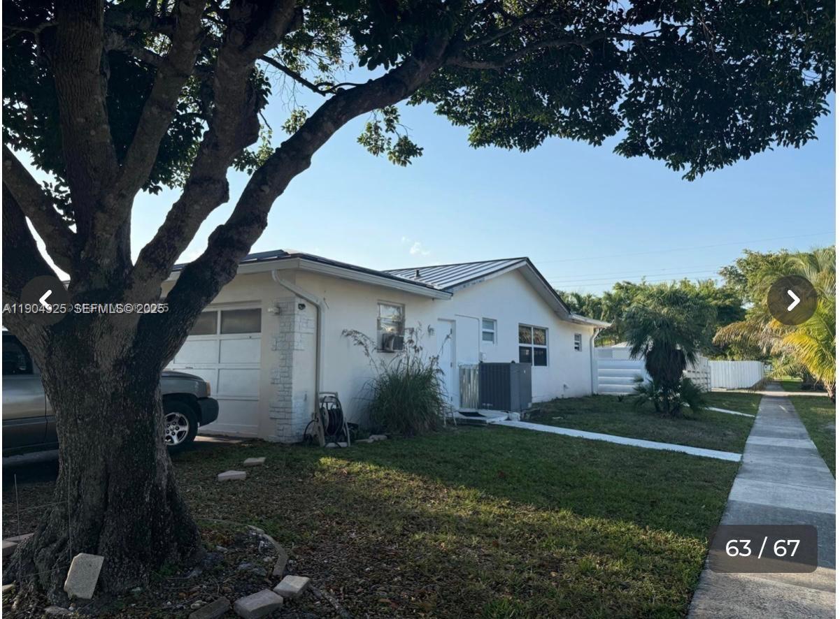5001 Madison Street Hollywood, FL 33021 - Photo 23 of 23 a view of a white house next to a yard with a large tree
