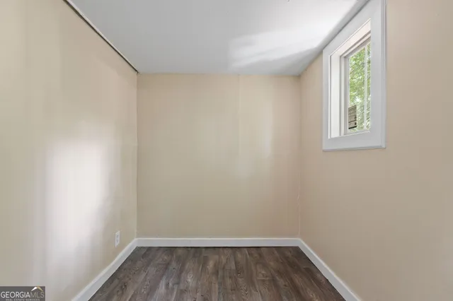 a view of a room that has wooden floor and fan in it
