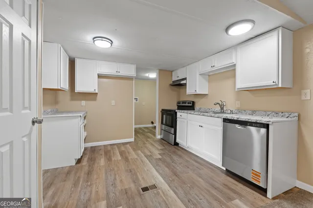 a kitchen with a refrigerator a stove top oven and wooden floor