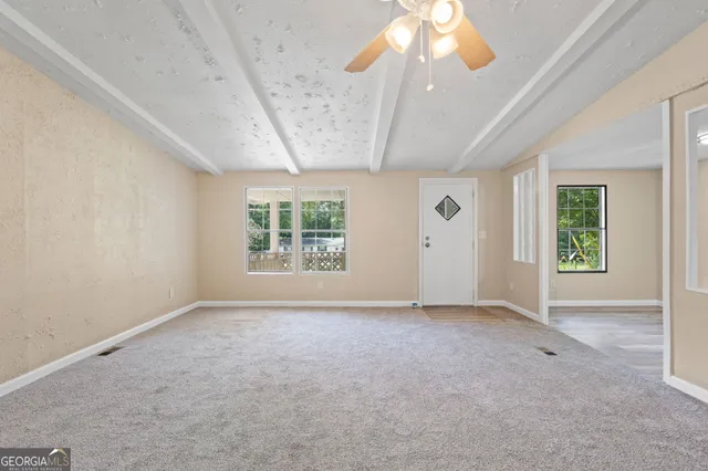 en empty room with windows and chandelier fan