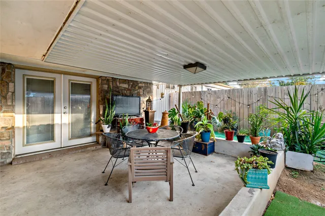 a view of a patio with table and chairs potted plants and floor to ceiling window