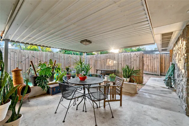 a patio with a table and chairs and potted plants