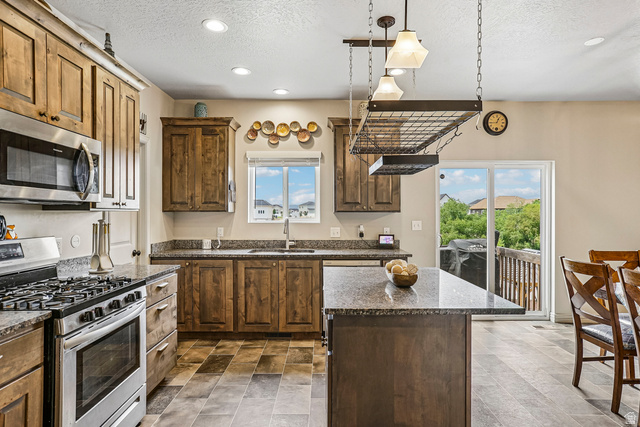 203 North 1900th Street West Mapleton, UT 84664 - Photo 10 of 48 Kitchen featuring wood-finish cabinetry, stainless steel appliances, granite countertops, and a central island