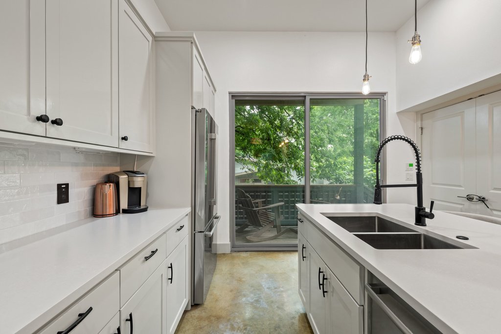 1131 Poquito Street, Unit A Austin, TX 78702 - Photo 11 of 34 a kitchen with stainless steel appliances granite countertop a sink a stove and a refrigerator with white cabinets