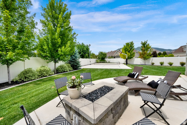 1132 South 1300th Street West Mapleton, UT 84664 - Photo 42 of 52 Outdoor living space featuring a paver fire pit, concrete patio, expansive lawn, white vinyl fencing, and mature trees