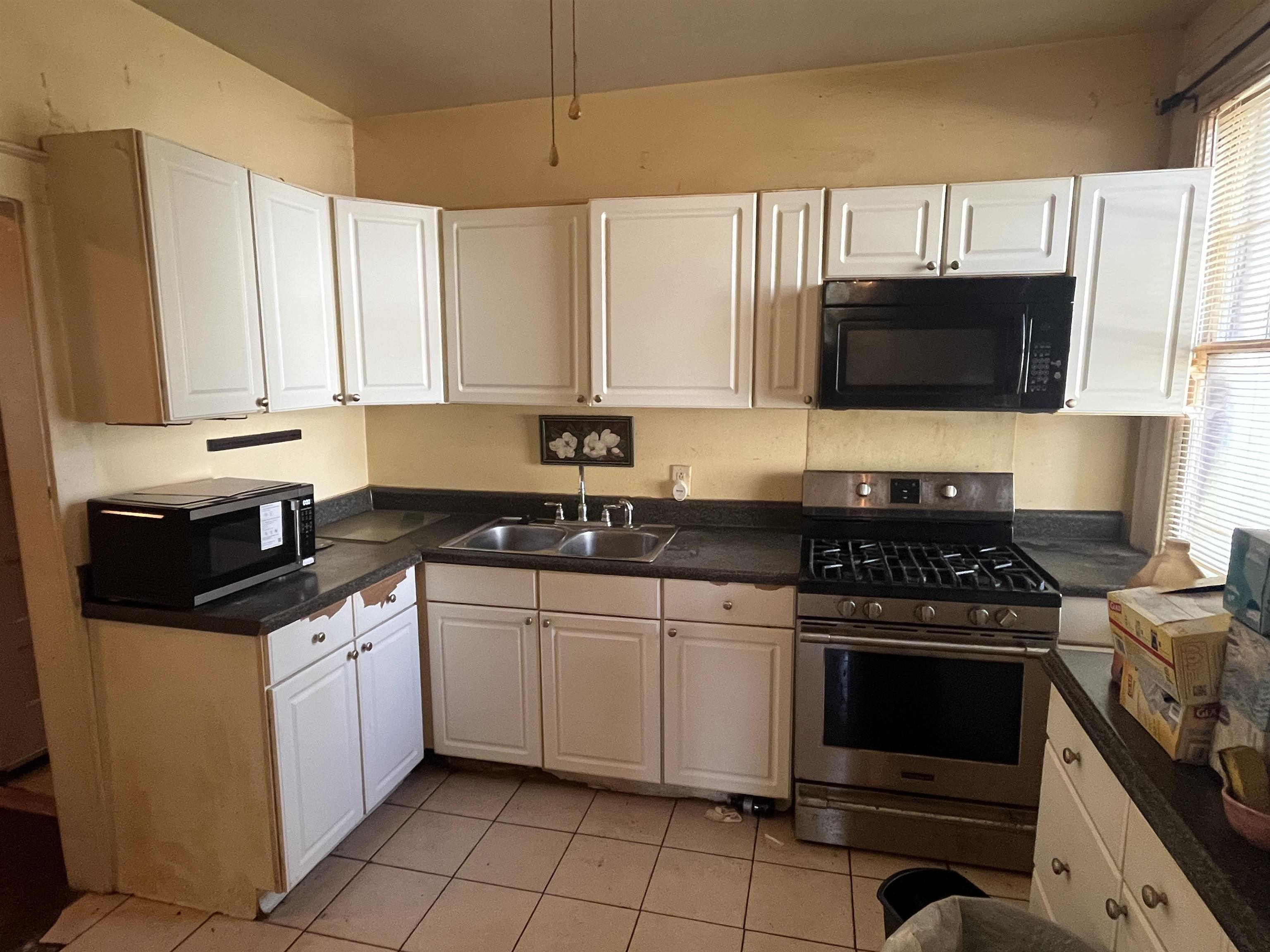 211 4th Street Mobile, AL 36611 - Photo 3 of 34 Kitchen featuring gas stove, dark countertops, white cabinetry, and black microwave