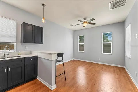 a view of a kitchen with a sink cabinet a ceiling fan and wooden floor