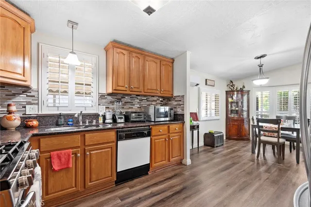 a kitchen with stainless steel appliances granite countertop a stove top oven a sink dishwasher a dining table and chairs with wooden floor