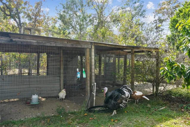an aerial view of a residential houses with outdoor space and trees all around