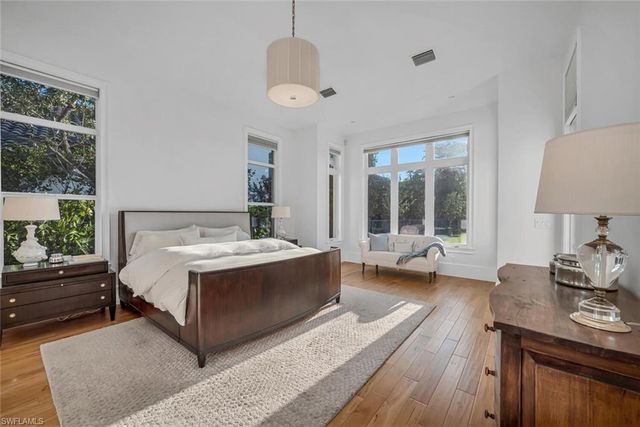 a spacious bedroom with a bed and wooden floor