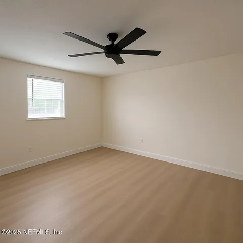 an empty room with a window and a fan