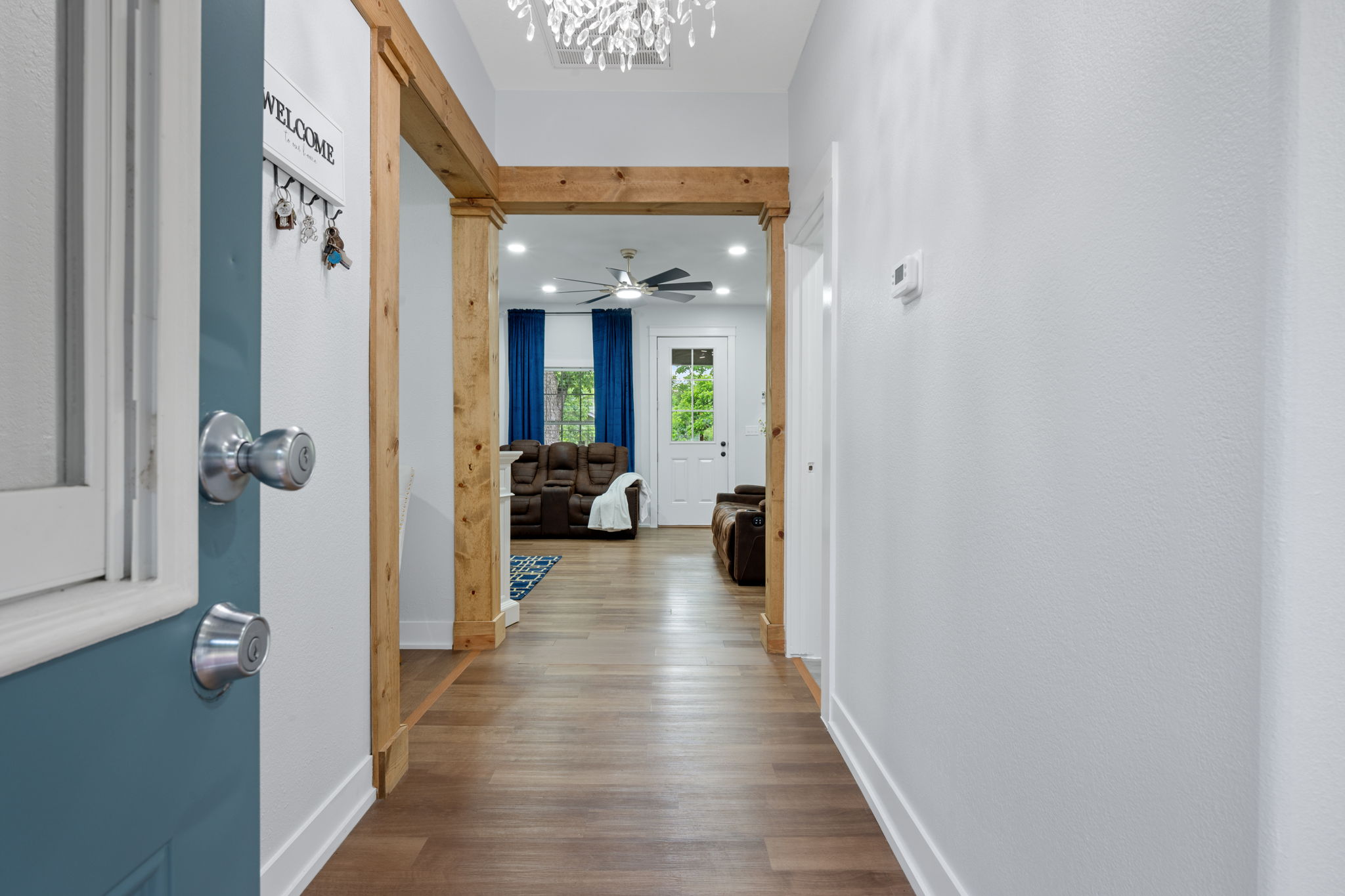 602 East 6th Street Cameron, TX 76520 - Photo 6 of 40 Entryway featuring wood-finish flooring extending throughout, a decorative light fixture, and a solid wood beam archway