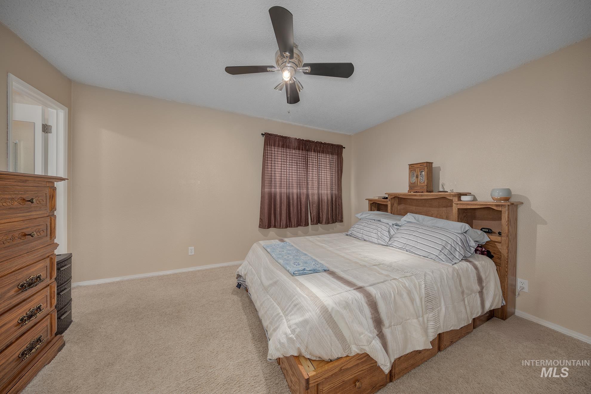 611 West Indianhead Road Weiser, ID 83672 - Photo 13 of 34 Bedroom featuring a ceiling fan, light colored carpet, and a textured ceiling