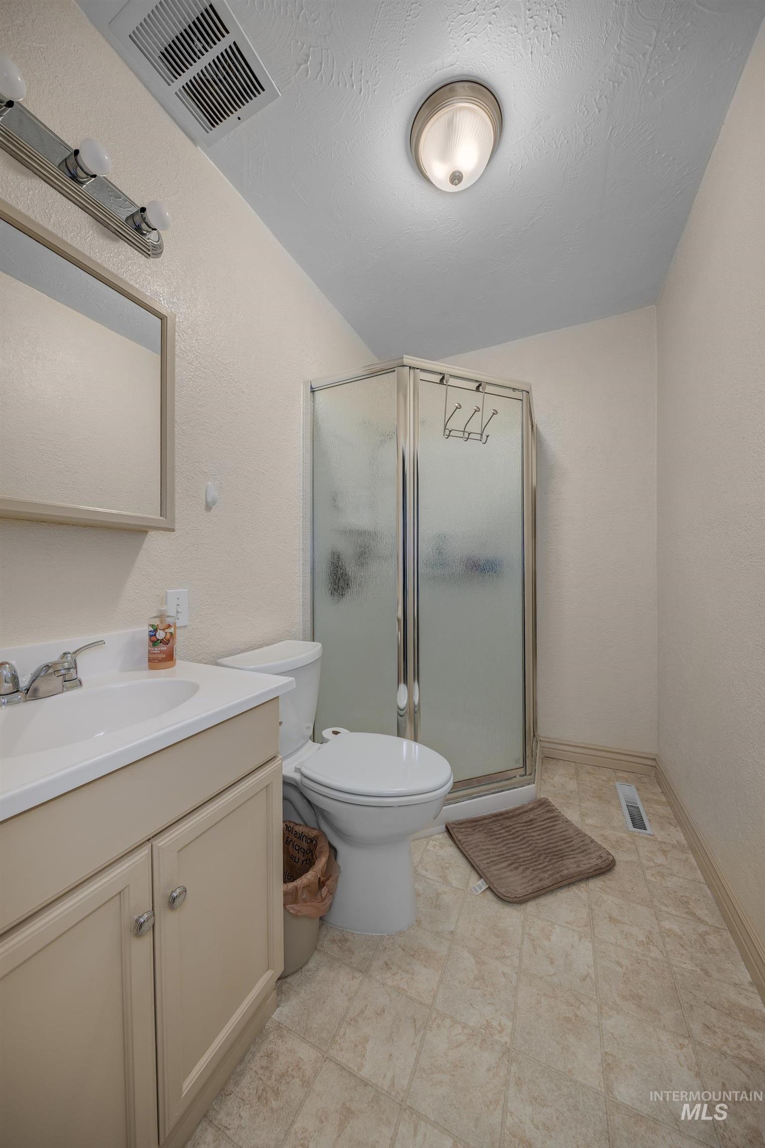 611 West Indianhead Road Weiser, ID 83672 - Photo 14 of 34 Bathroom featuring a shower stall, vanity, a textured wall, and lofted ceiling