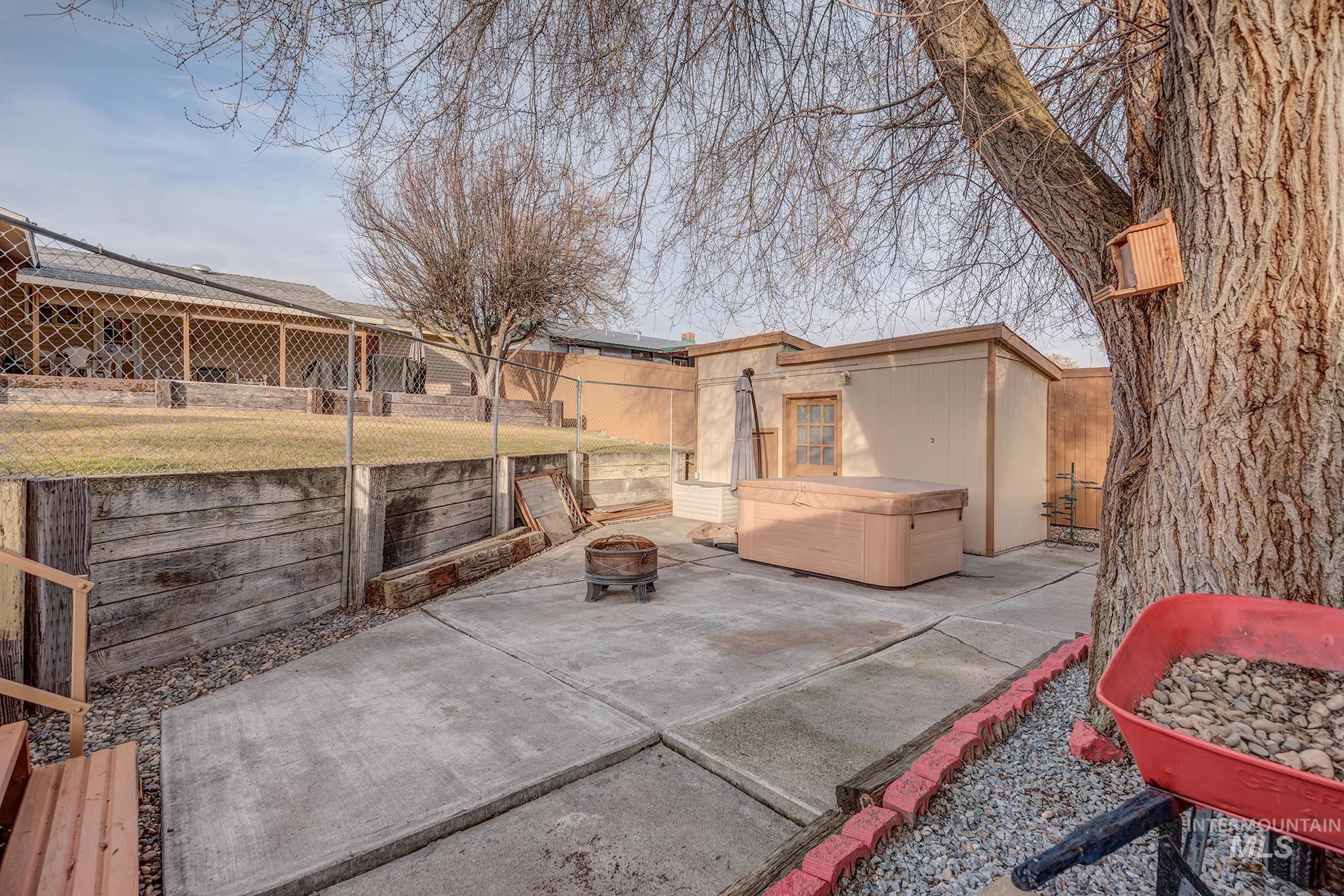 611 West Indianhead Road Weiser, ID 83672 - Photo 29 of 34 Fenced backyard featuring a hot tub, an outdoor structure, a patio area, and a fire pit
