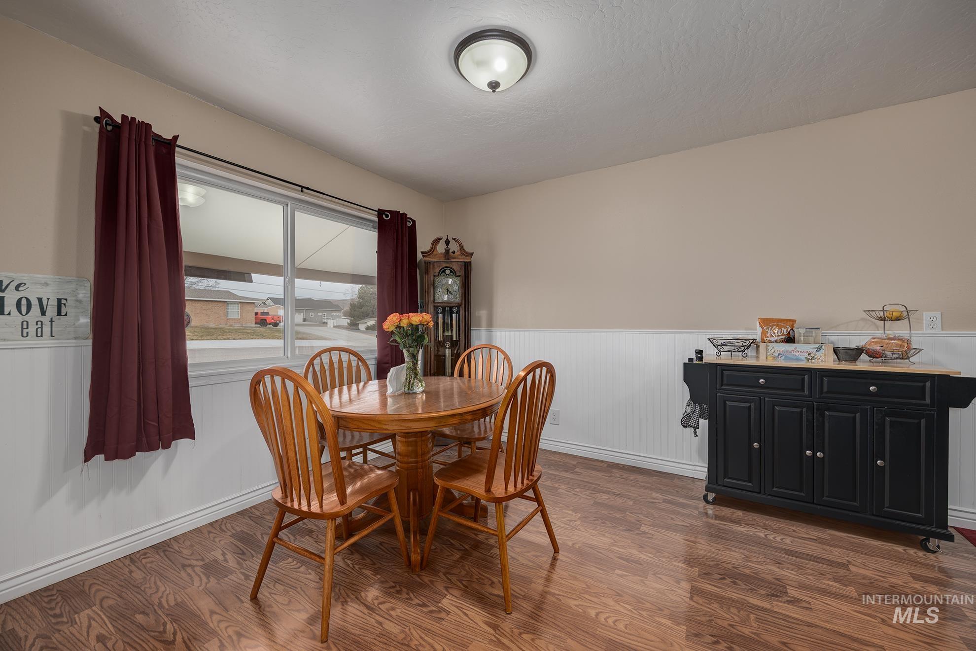 611 West Indianhead Road Weiser, ID 83672 - Photo 7 of 34 Dining space featuring dark wood-style flooring and a wainscoted wall