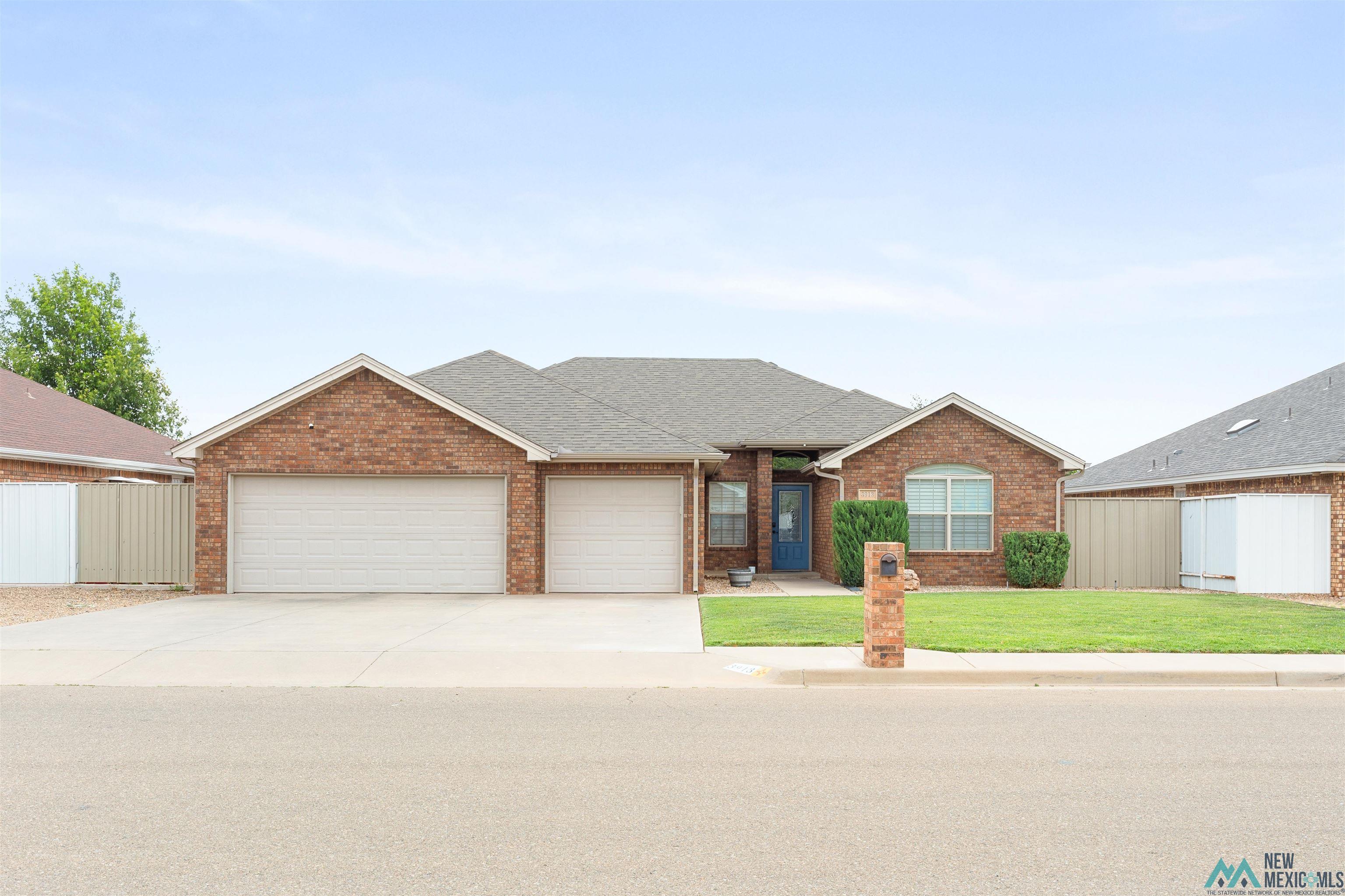 3913 Woodlark Road Clovis, NM 88101 - Photo 1 of 28 Brick exterior featuring a two-car garage, a covered entry with a blue door, and an arched window