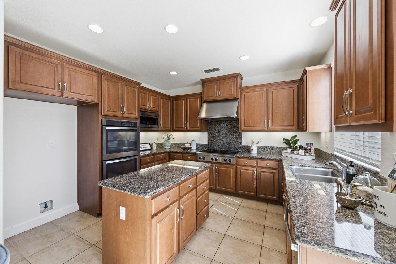698 West Rico Way Tracy, CA 95391 - Photo 16 of 48 a kitchen with kitchen island granite countertop a sink stove and refrigerator