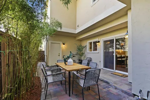 a patio with table and chairs and potted plants