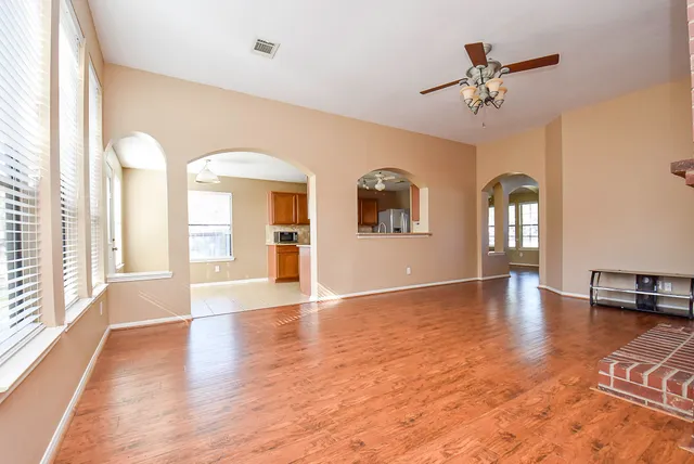 a view of an empty room with window and wooden floor