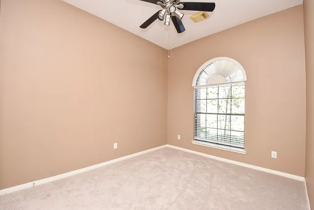 an empty room with a window and a ceiling fan