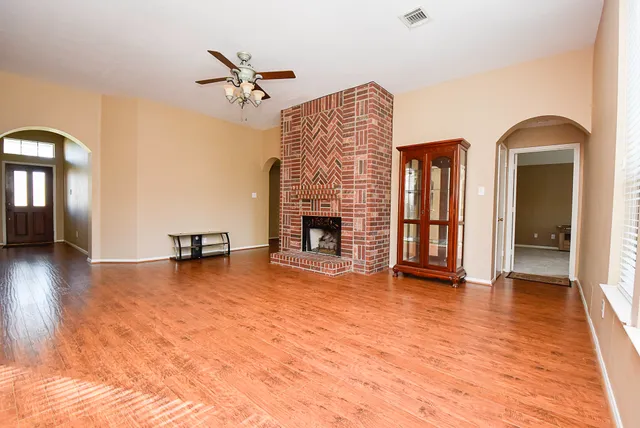 a view of an empty room with window a fireplace and wooden floor