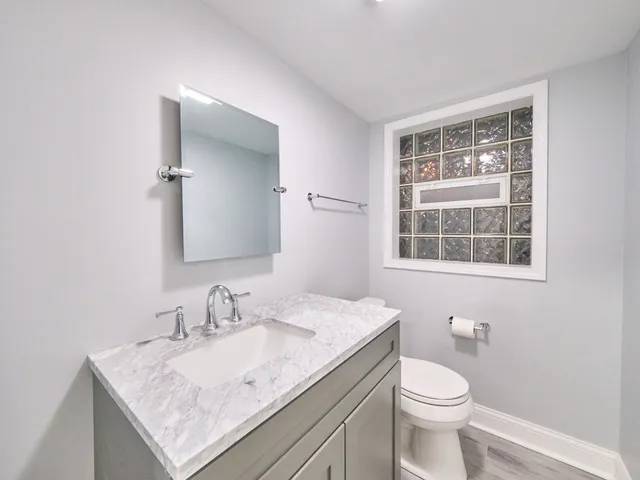 a bathroom with a granite countertop sink a toilet and a window
