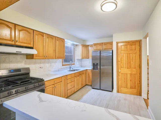 a kitchen with stainless steel appliances granite countertop a stove a sink and a refrigerator