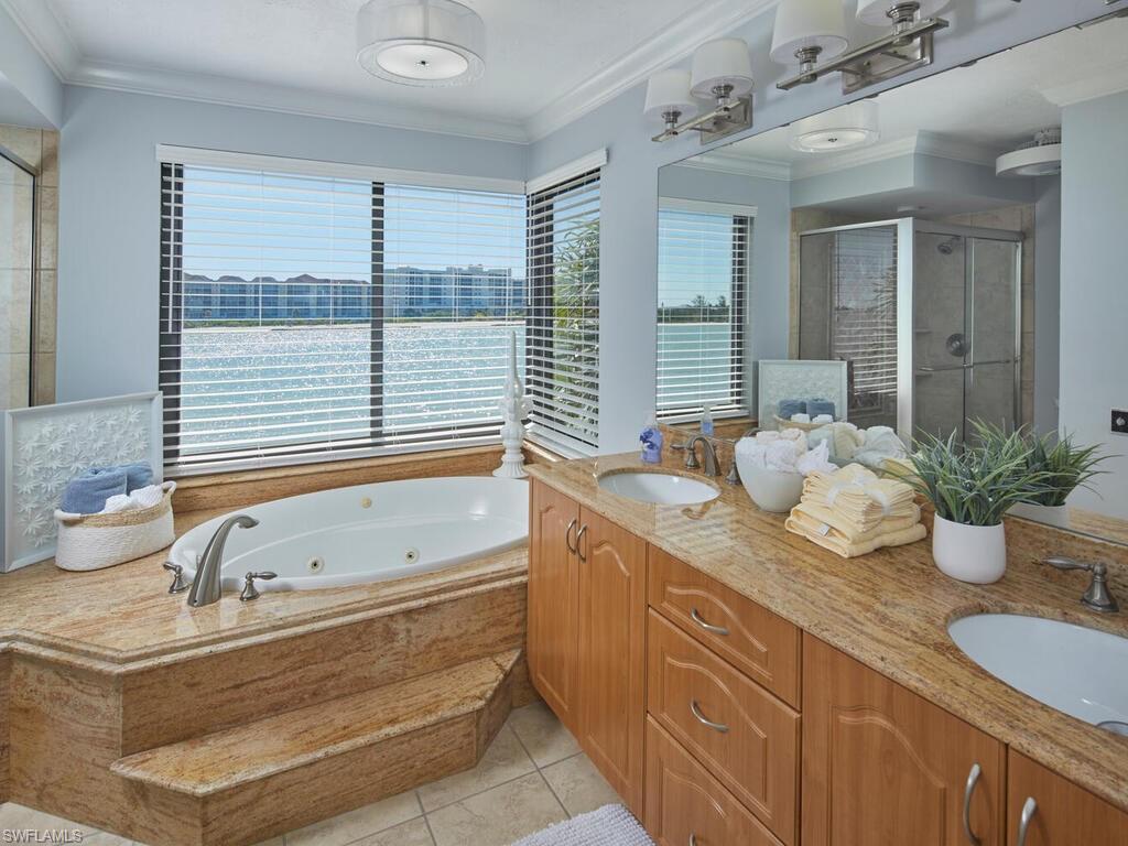 324 La Peninsula Boulevard, Unit 324 Naples, FL 34113 - Photo 13 of 35 a bathroom with a tub sink and mirror