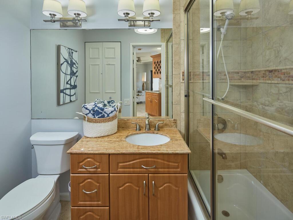 324 La Peninsula Boulevard, Unit 324 Naples, FL 34113 - Photo 16 of 35 a bathroom with a granite countertop sink a toilet and shower