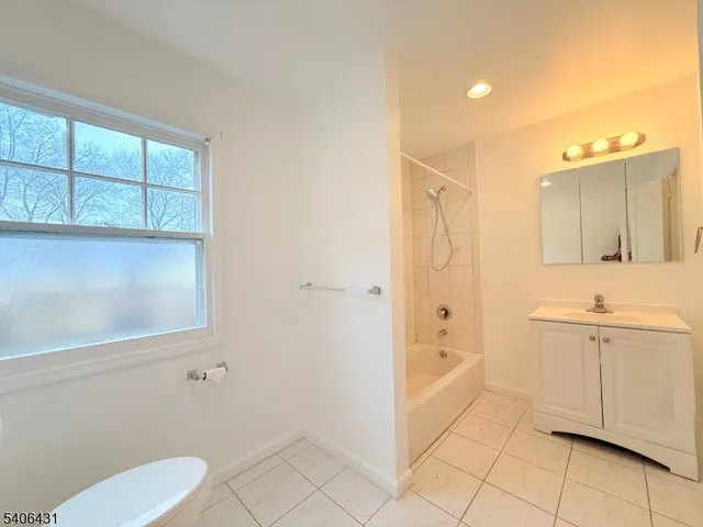 a view of an empty room with window and chandelier fan