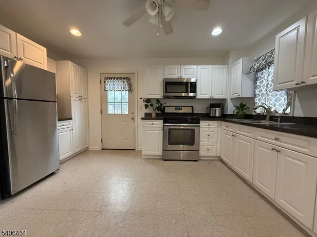 a kitchen with granite countertop white cabinets and stainless steel appliances