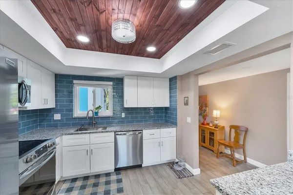 a kitchen with stainless steel appliances granite countertop a refrigerator a sink a stove and cabinets