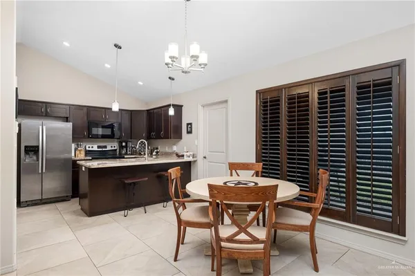 a kitchen with a dining table chairs and refrigerator